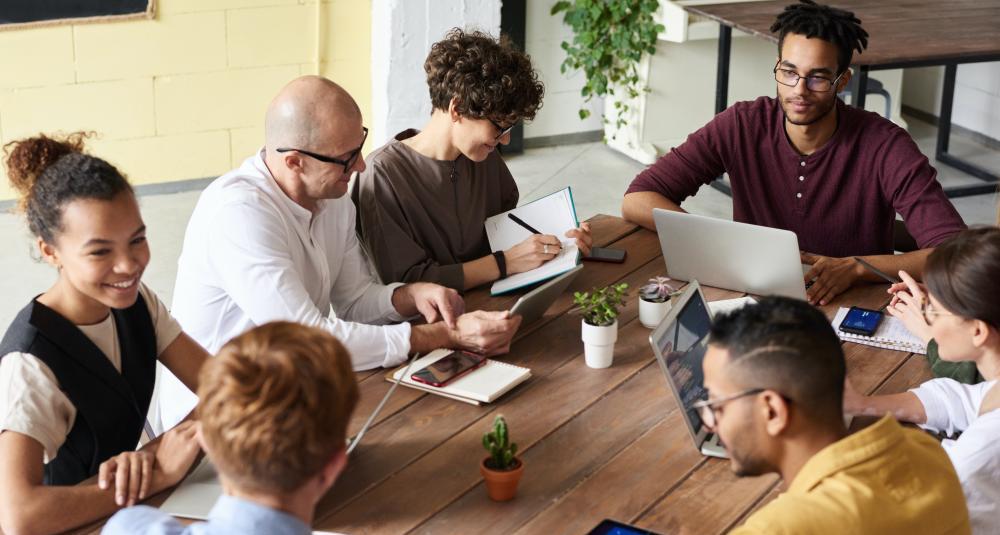 Smiling coworkers sitting around conference table having a discussion