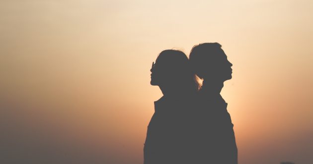 Silhouette of couple standing back to back