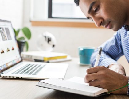 Man at desk writing in notebook