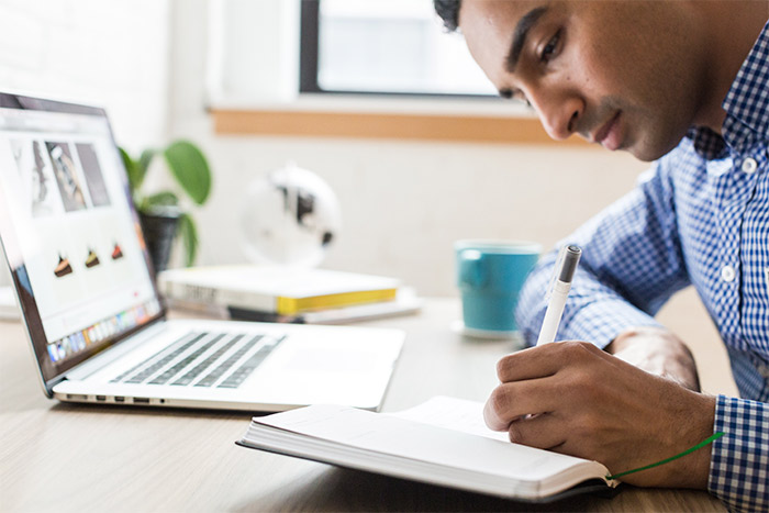 Man at desk writing in notebook