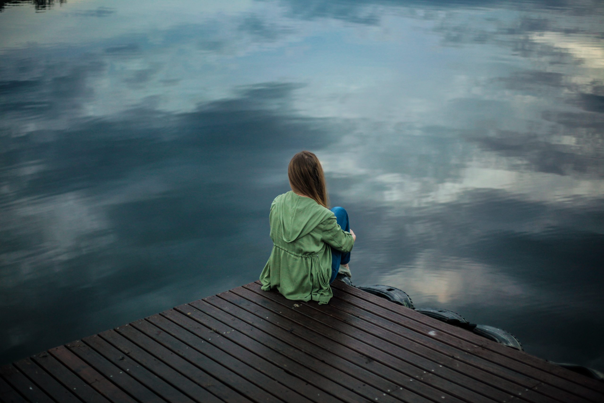 photo of a girl sitting alone on dock