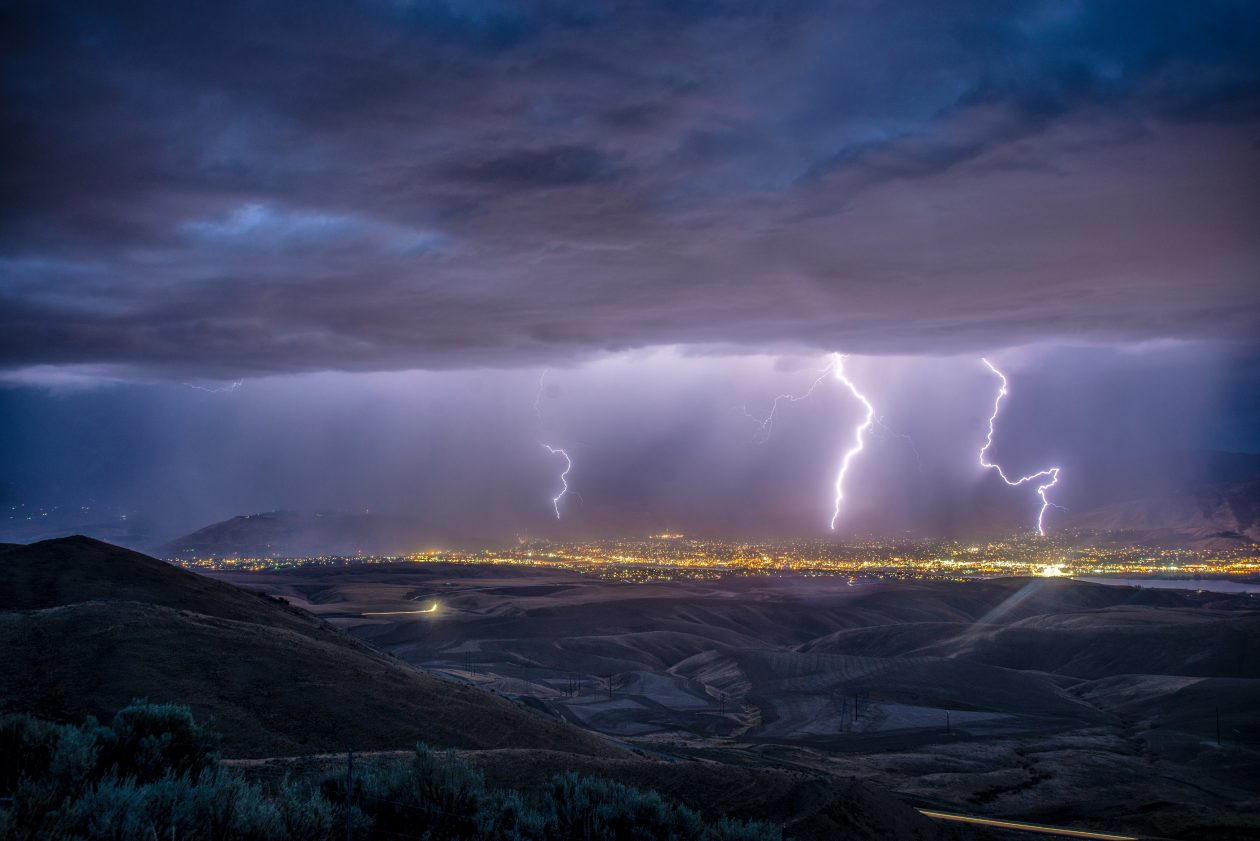 Lightning striking a distant city in a valley