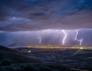 Lightning striking a distant city in a valley