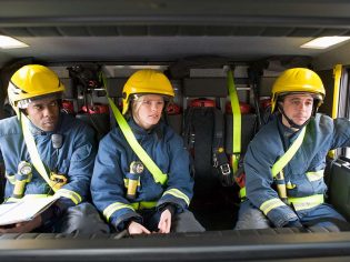 Firefighters in gear sitting inside a fire truck